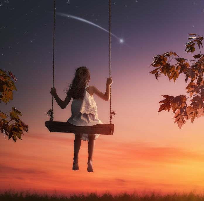 Happy child girl on swing in sunset summer. Kid makes a wish by seeing a shooting star.